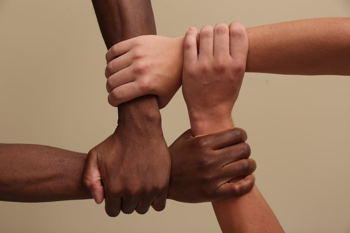 Men Joining Hands Together on Beige Background, Closeup